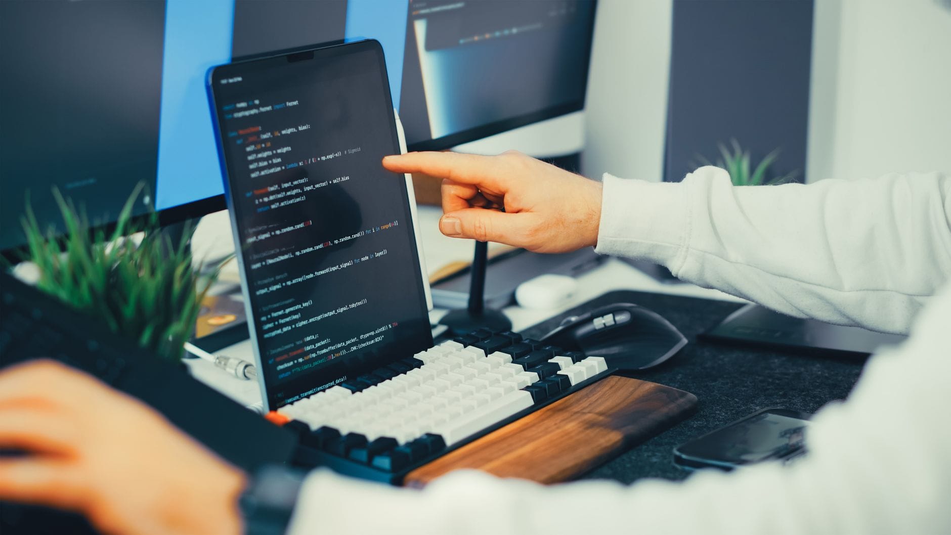 Programista pracuje nad kodem przy laptopie i monitorze w biurze